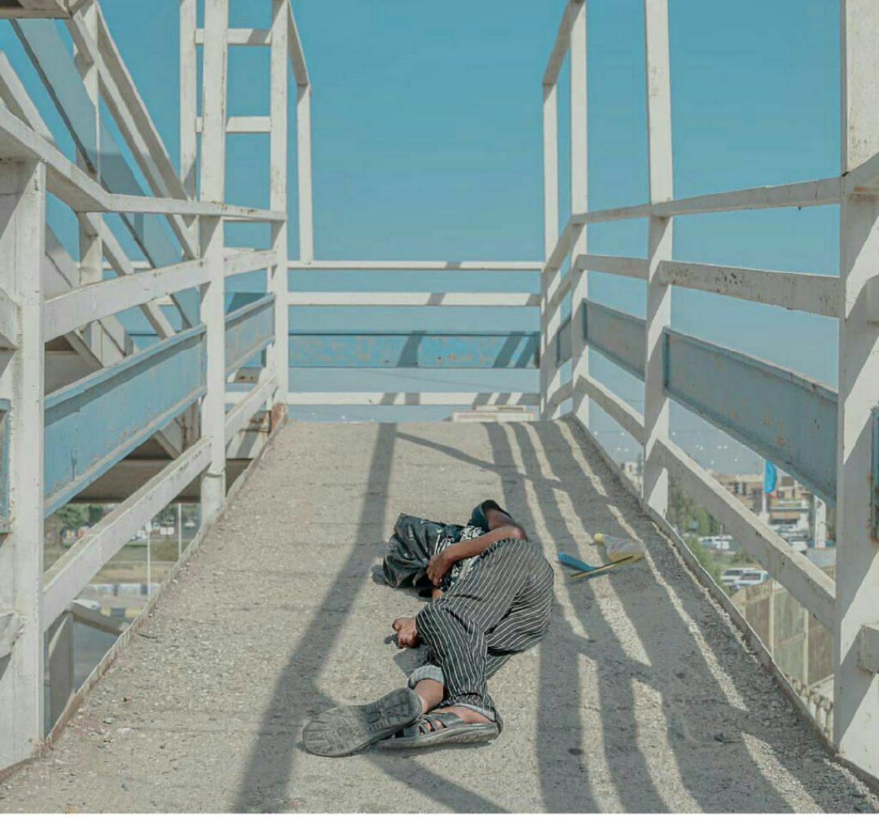 تصویری تلخ در اهواز که معروف شد  🔹تصویری تلخ از استراحت کودک کار اهوازی روی آسفالت داغ یکی از پل‌ها